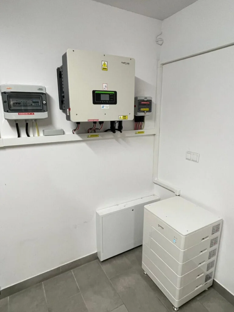 Inwertery hybrydowe – ścienny falownik z panelem sterowania i moduły magazynu energii w pomieszczeniu technicznym